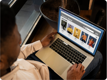 Person browsing an online fashion store on a laptop with t-shirt product listings